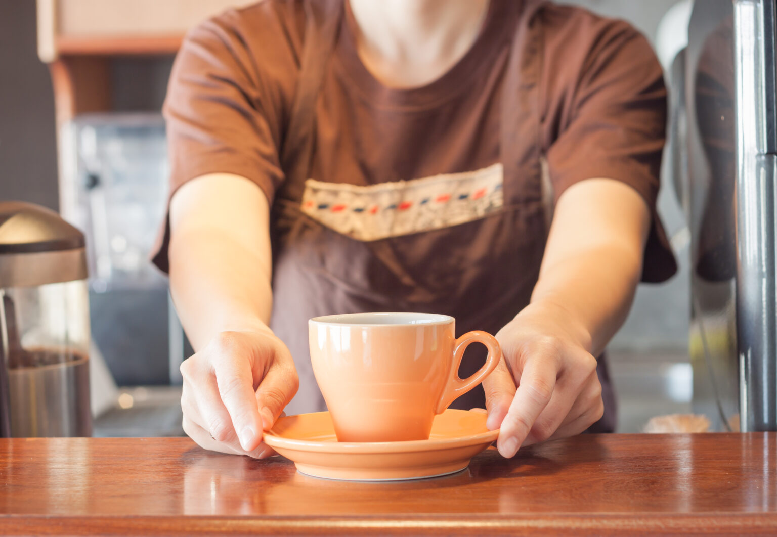 Two hands reaching out, offering a cup of coffee